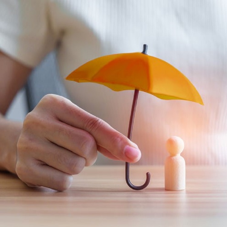 Hand holding a miniature umbrella over a wooden figure